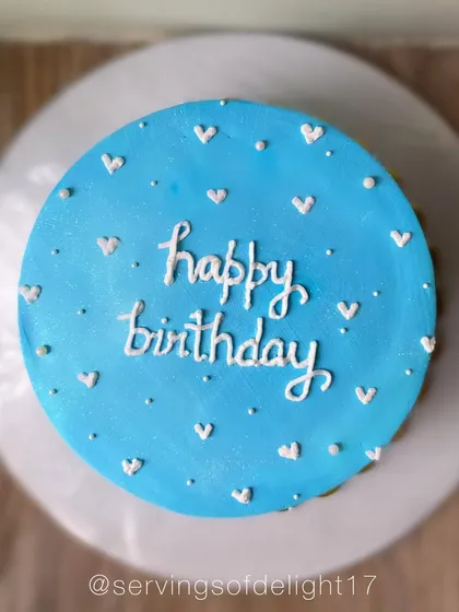 A simple and sweet blue birthday cake dotted with tiny white hearts. It's a minimalist design that's full of charm.