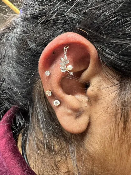 A nature-inspired ear stack with a leaf and pearl hanging, complemented by simple solitaire studs.