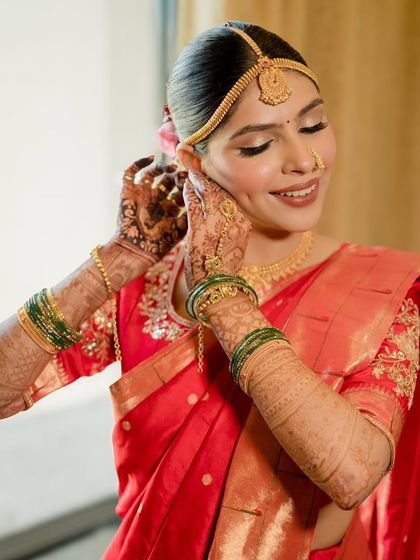 A candid moment of the bride putting on her earrings. The soft, glowing makeup looks beautiful in the natural light.