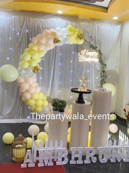 A soft and elegant ring decoration with pastel yellow and white balloons. The fairy lights in the backdrop add a magical, twinkling effect.