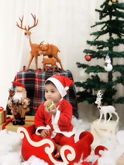Dressed as Santa's little helper, this child sits in a sleigh amidst a winter wonderland setup. Our Christmas mini-sessions are perfect for creating holiday cards.