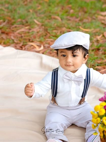 This little gentleman is dressed up in a white shirt, suspenders, and a cap for his outdoor picnic-themed milestone shoot.