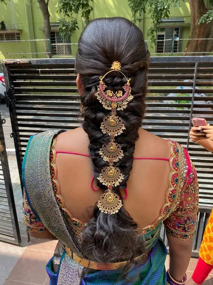 An engagement look featuring a messy braid adorned with traditional temple jewellery. This is a beautiful fusion of modern technique and classic accessories.