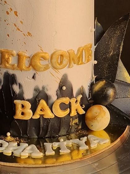 A close-up of the 'Welcome Back' lettering and the black and gold details on the graduation cake.