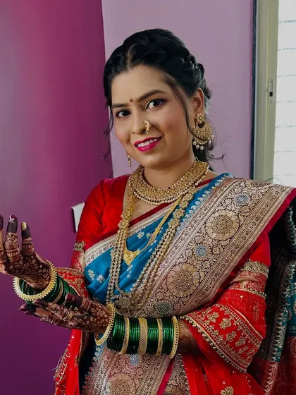 A full view of the bride's look, showcasing the beautiful Paithani saree, layered gold necklaces, and the happy smile that completes the picture.