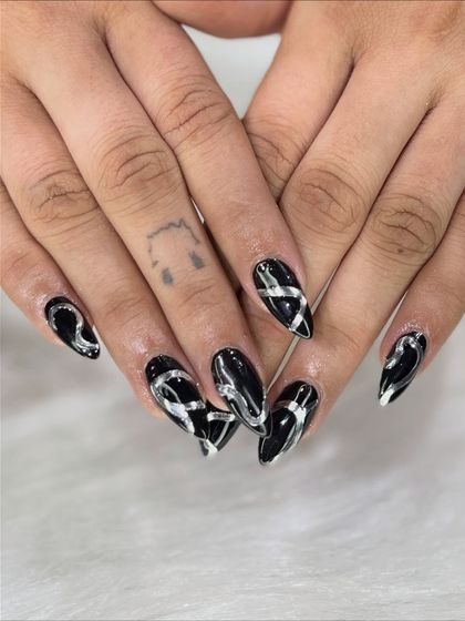 A clear, top-down view of the bold silver swirls on the black stiletto nails.