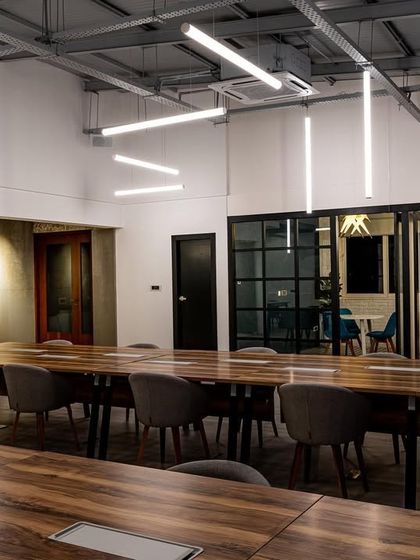 A different perspective of the sculptural lighting installation. Notice how the light is bright enough for tasks but diffused to prevent harsh shadows or glare on screens, which is crucial for a comfortable working environment.