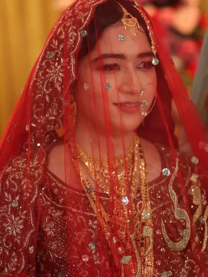 A candid shot of the Nikah bride through her veil, capturing a moment of quiet joy. The makeup looks soft and ethereal.