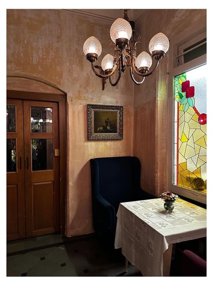 Another intimate corner at The Lovefools, perfect for a quiet conversation. The vintage-style armchair, stained-glass window, and classic chandelier all contribute to the restaurant's timeless and soulful character.