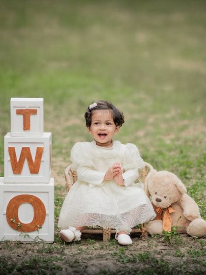Celebrating two! An outdoor second birthday photoshoot with "TWO" blocks and a teddy bear friend.