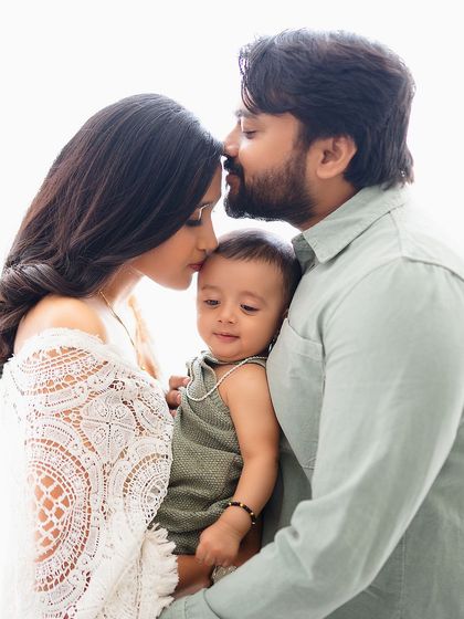 A tender moment with both parents kissing their baby's head.
