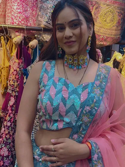 A client trying on a grey-blue lehenga with a unique pink and blue sequin blouse, showing off a contemporary ethnic look.
