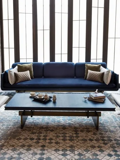 This living room setting demonstrates a meticulous balance of materials. A deep blue suede sofa is flanked by two cantilevered lounge chairs in a rose gold metal finish, creating a symmetrical and sophisticated arrangement.