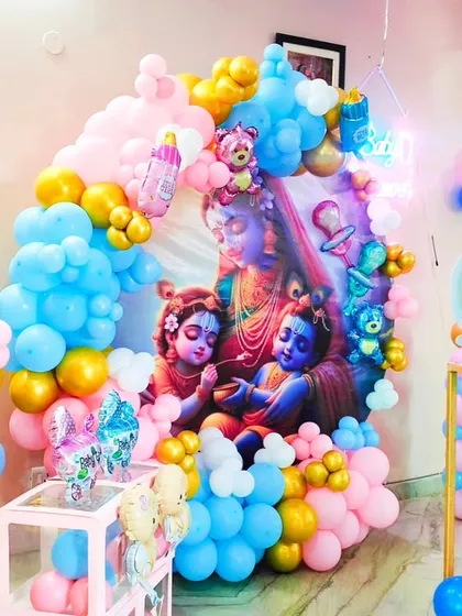 A close-up of the stunning Kanha ji backdrop, framed by a vibrant balloon arch. The mix of pink, blue, and gold balloons makes the artwork pop.