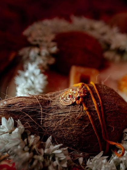 A close-up of a sacred thread ('Thali') resting on a coconut, a significant detail in a South Indian wedding ceremony.