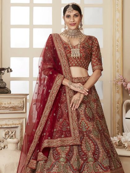 A full-length shot of a model in a beautiful maroon and green bridal lehenga. The rich colors and paisley motifs create a timeless and sophisticated look.