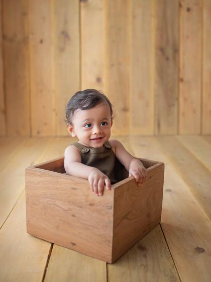 Peek-a-boo! A simple wooden box can be the best prop for a curious toddler during a milestone photoshoot.