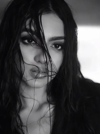 This black and white photo has a classic, cinematic quality. The dramatic makeup and hair styling give it a timeless appeal, suitable for a fashion magazine cover.