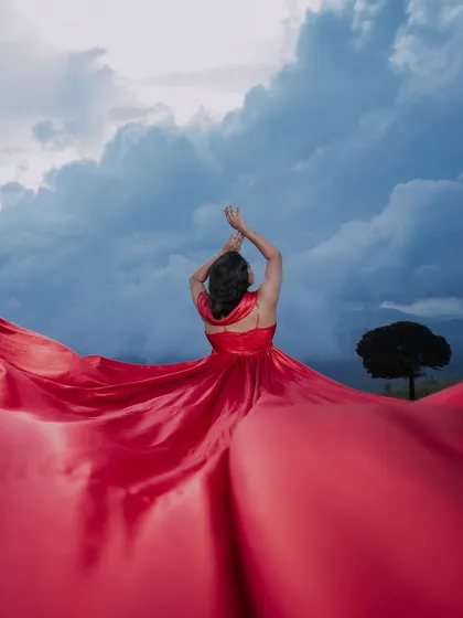 A dramatic solo portrait of the bride-to-be, with her vibrant red gown against a stormy sky. This shot showcases our artistic and creative approach to pre-wedding photography.