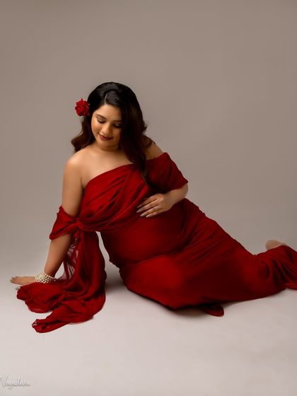 A soft and romantic seated pose in a red drape. The flower in her hair adds a touch of classic beauty.