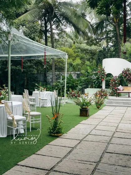 A wide view of an Indo-Western wedding setup in a lush garden. The combination of clear-top tents, elegant table settings, and a beautifully decorated stage creates a seamless flow.