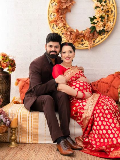 Seated together in a traditional setting, this couple's portrait is a beautiful blend of cultural elegance and the universal joy of expecting a child.