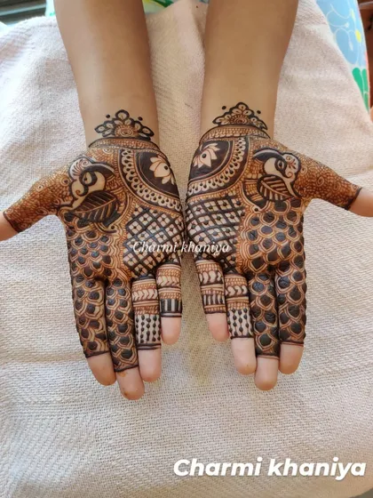 A striking peacock mehendi design. The contrast between the filled and empty spaces really makes the details of the peacock's feathers and the check pattern on the palm stand out.