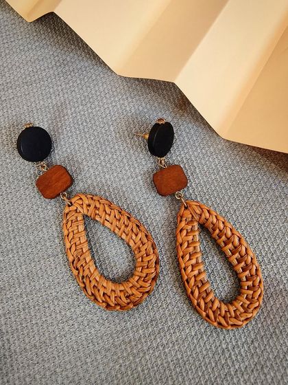 The vintage oval hand-woven straw earrings in black and brown, a classic bohemian accessory.