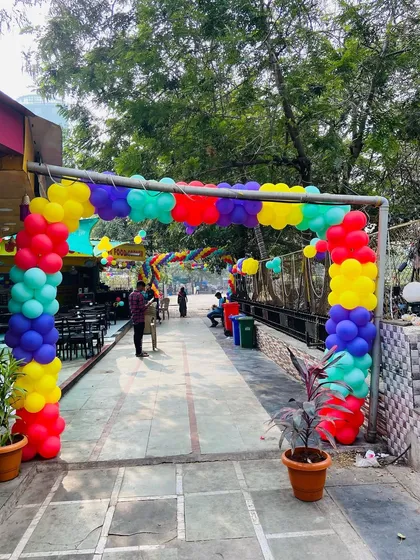 The entrance gate of an outdoor venue decorated with a colorful balloon arch.