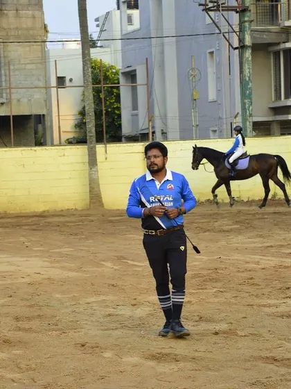A trainer stands in the arena, whip in hand, ready for the next lesson. This image captures the discipline and focus that our coaching staff brings to every session.