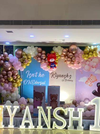For a child's first birthday, I can create a magical world. This "ONEderful" teddy bear theme includes a full stage setup with custom backdrops, a multi-colored balloon arch with rose gold and chrome accents, and large marquee letters spelling out the birthday boy's name.