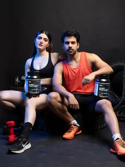 A key shot for e-commerce, featuring both male and female models presenting the whey protein supplements directly to the camera. This composition is effective for building trust and is ideal for landing pages or Amazon A+ content, clearly displaying the product in a relatable fitness context.