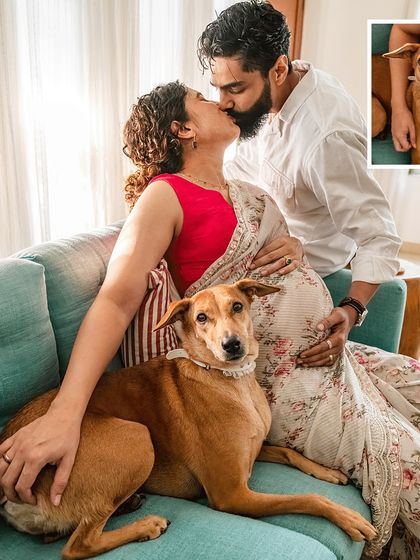 An elegant maternity portrait with a furry friend. This shot captures a tender kiss between the couple while their Indie dog sits calmly, a central part of their growing family.