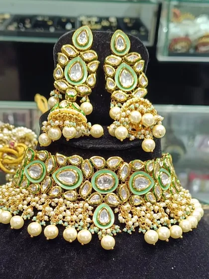 A heavy uncut kundan choker set in a lovely pastel green color, complete with matching jhumkas and pearl drops.