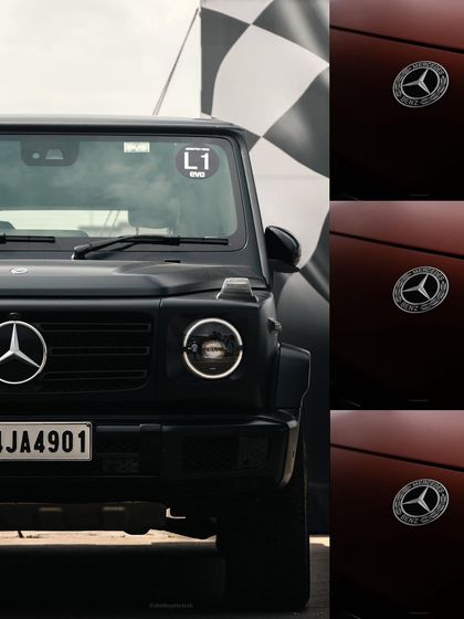 A creative composition featuring the front of a black Mercedes G-Wagon next to the brand's logo. This shot plays with branding and the vehicle's iconic, powerful stance.
