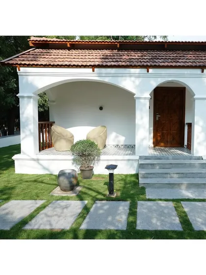 A closer look at the veranda design, where comfort is key. The space is designed to be a cozy nook for reading or conversation, protected from the elements while still feeling open to the garden. The patterned floor tiles and simple, comfortable seating complete this inviting outdoor room.
