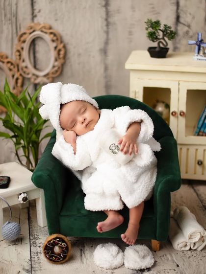 A sleepy spa guest. Dressed in a tiny bathrobe, this newborn is the picture of tranquility in our custom-designed miniature living room set.