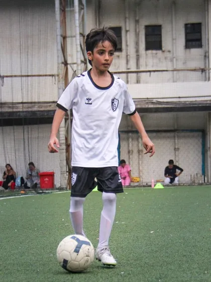 With complete focus, a young player controls the ball, preparing for his next move during a practice session.