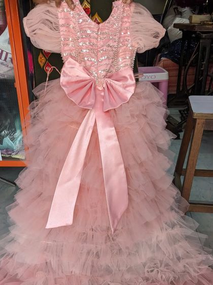 A custom-ordered baby girl's birthday frock with ruffle layers and a large satin bow on the back. I can create any design you have in mind.