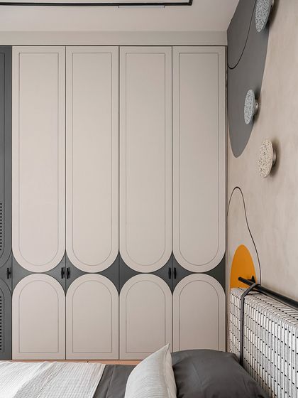 A close-up of the custom wardrobe in the kids' room. The doors feature a unique arched design that adds a soft, playful touch while tying in with other curved elements in the space.