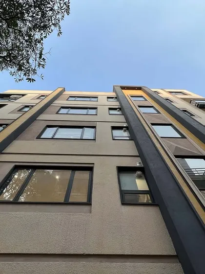 An upward-looking perspective of the Yellow Line Apartment facade. This angle emphasizes the verticality of the design and the interplay of the different colored bands against the sky.