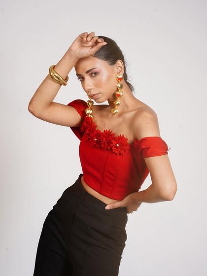 A powerful pose highlights this red off-shoulder top with floral details. I paired it with statement heart-shaped earrings and a gold cuff to create a bold, fashion-forward look.
