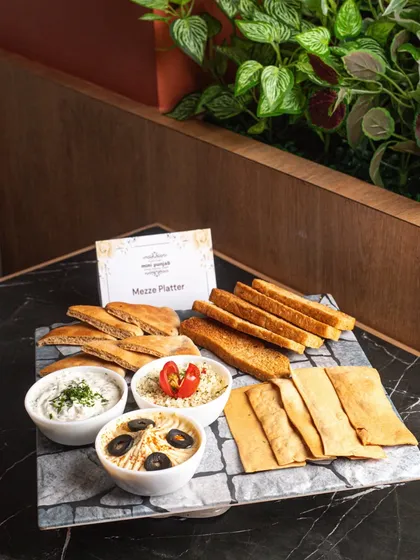 A beautifully arranged Mezze Platter, complete with hummus, dips, pita bread, and lavash. This is a perfect sharing platter for any social gathering.