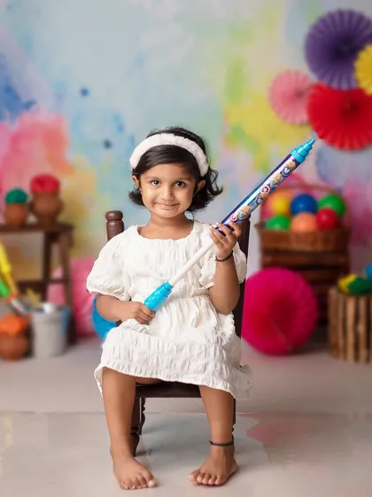 A little girl sits patiently with her pichkari, waiting for the Holi fun to begin.