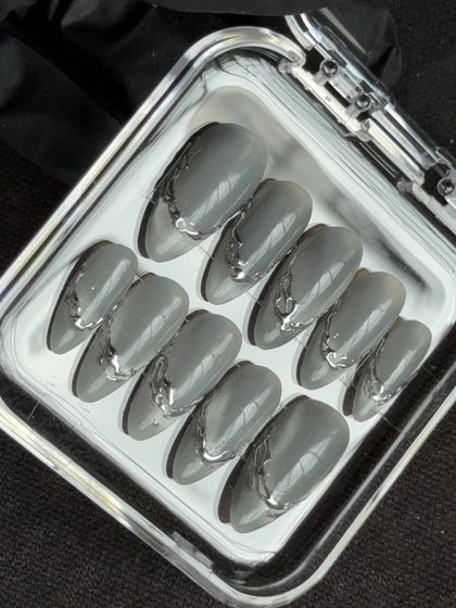 A clear shot of the finished silver chrome press-on nails in their case. This design is perfect for someone who wants a unique, minimalist look with an artistic, three-dimensional twist.