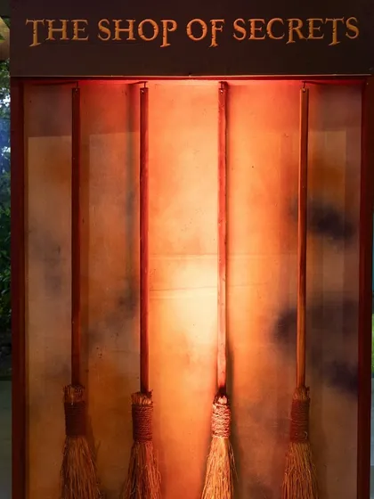 A display case showcasing "The Shop of Secrets," featuring a collection of wands and broomsticks for aspiring wizards.