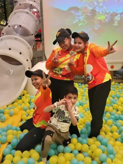 Our staff, the Tinga Superstars, are always ready to play! Here, they pose with a happy child in the middle of our massive ball pit.