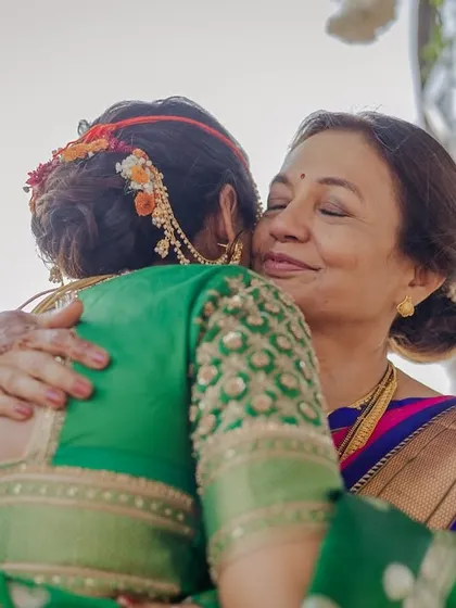 A heartfelt hug between the bride and her mother. This angle showcases the beautiful floral arrangement on her traditional bridal bun.