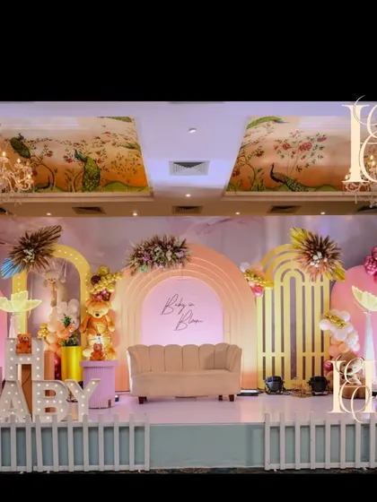 The main stage for a "Baby in Bloom" and teddy bear-themed baby shower. The elaborate setup includes multiple arched backdrops, "Oh Baby" marquee lights, a picket fence accent, and a mix of pampas grass and balloon arrangements.
