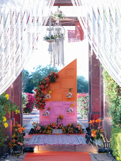 A grand and colorful entrance for a 'Gypsy Garden High Tea', with a vibrant pink and orange photo wall adorned with cascading flowers.